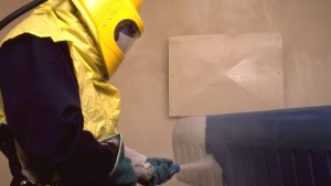 Professional worker in protective gear performing surface cleaning, ideal for truck frame sandblasting near me services