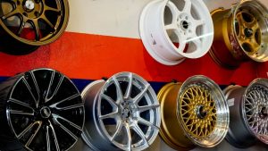 A variety of car rims in different colors and styles, displayed on a wall, showcasing options available for sandblasting rims near me.