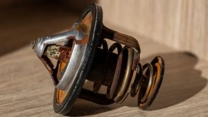 Close-up of a rusty metal automotive part on a wooden surface, ideal for restoration through small parts sandblasting services near me.