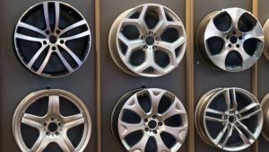 Display of different styles of aluminum rims on a wall, showing smooth finishes and clean details after sandblasting aluminum rims for restoration and customization.