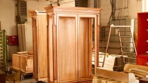 Large wooden cabinet in a workshop, restored to a smooth finish through sandblasting wood furniture for refinishing and durability.