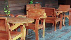 Set of polished wooden chairs and tables on a patio, showcasing the smooth finish achieved by sandblasting wood furniture for restoration and refinishing.