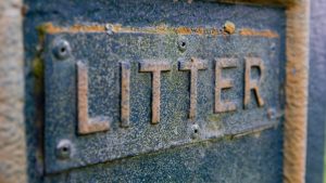 Close-up of a weathered metal sign labeled "LITTER," showing rust and texture, example for how to sandblast surfaces.