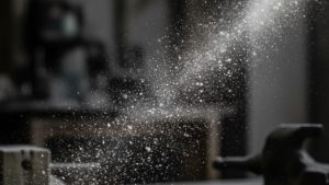 Close-up of sandblasting dust particles in the air, demonstrating the potential health risks associated with sandblasting, including the importance of proper dust control in the sandblasting process.
