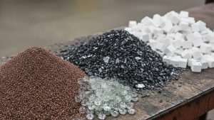 Different types of abrasive materials used for sandblasting, including crushed glass, plastic media, and soda, which affect the average cost to sandblast a car.