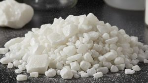 Close-up of white crystalline material, resembling sugar, with rough edges, which can be used as aluminum oxide sandblasting media for surface preparation and cleaning.