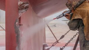 Worker sandblasting metal surface, showing conditions related to will sandblasted stainless steel rust