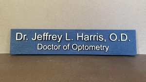 Dimensional office sign for an optometry practice with raised lettering on a textured blue background