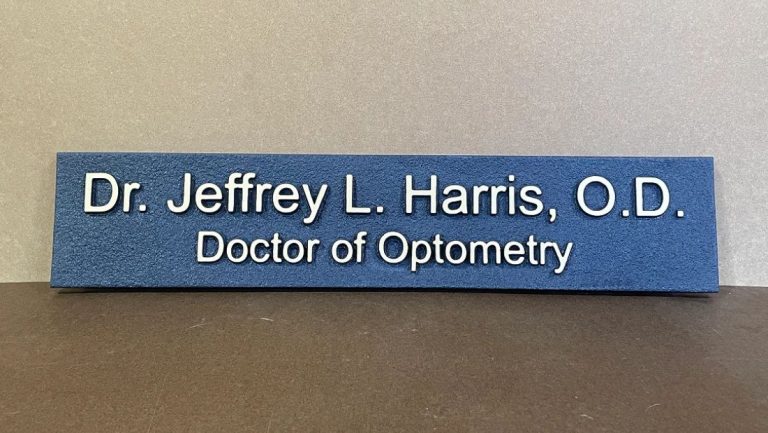 Dimensional office sign for an optometry practice with raised lettering on a textured blue background