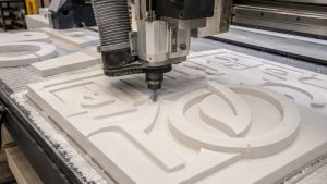 CNC router cutting detailed lettering into an HDU sign panel