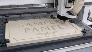 CNC router cutting recessed lettering, borders, and decorative details into an HDU sign panel.